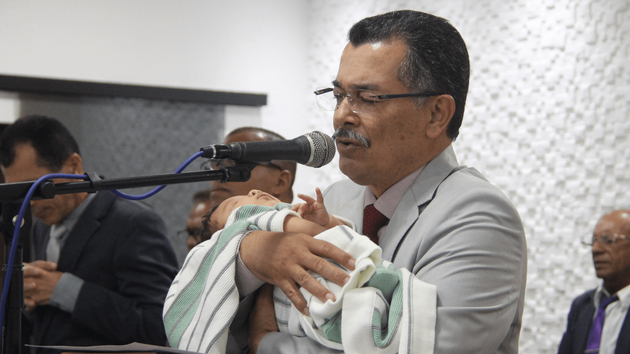 Pastor Cláudio Lemos apresenta criança no final do culto.